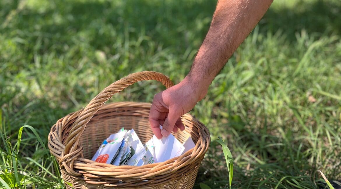 Eine Hand greift in einen Korb voller Postkarten.